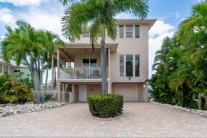 A two-story residential building with a balcony, a garage, and a paved driveway. - Island Pearl (Fort Myers Beach)