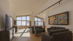 Ein modernes Wohnzimmer mit großem Fenster, Flachbildfernseher und einem Gemälde an der Wand.