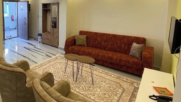 A modern living room with a sofa, armchairs, a coffee table, and a TV. - Otel Batur (Taskopru)