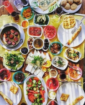 A table with various dishes including salads, meats, and desserts, suggesting a meal setting.