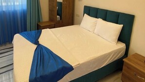 A hotel room with a large bed, a wooden wardrobe, a mirror, and a window with curtains. - Otel Batur (Taskopru)