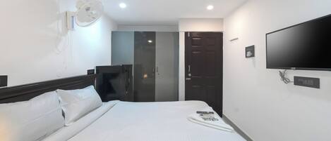 A hotel room with a bed, a TV, a wardrobe, and a mirror.