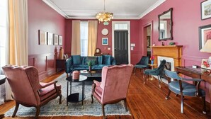 Un salon avec un canapé de couleur turquoise, des fauteuils roses et une table basse.