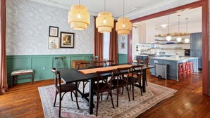 Un coin repas avec une table et des chaises en bois, un tapis à motifs et des suspensions en osier.