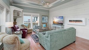 A spacious living room with a high ceiling, a fireplace, and a large window. - Spacious Crystal Beach Home | | Hot Tub | Walk to Beach | Sleeps 18 (Crystal Beach)