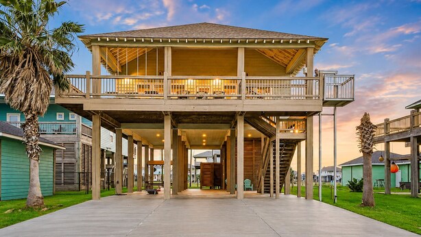 A two-story building with a balcony, a covered walkway, and a central open space. - Spacious Crystal Beach Home | | Hot Tub | Walk to Beach | Sleeps 18 (Crystal Beach)