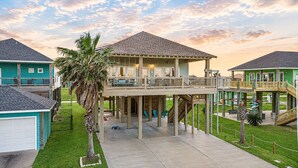 A multi-story building with a balcony, a covered outdoor area, and a staircase. - Spacious Crystal Beach Home | | Hot Tub | Walk to Beach | Sleeps 18 (Crystal Beach)