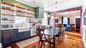 Una cocina moderna con estantes de madera, un comedor con mesa y sillas, y una sala de estar con sofá y televisor.