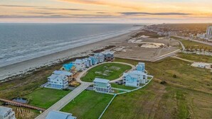 Una propiedad costera con varias edificaciones, una playa y un camino que lleva al océano.