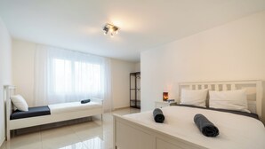A modern hotel room with a large bed, a smaller bed, and a walk-in closet. - Cozy 2-bedroom apartment in charming Safenwil with WiFi (Safenwil)