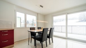 A modern kitchen with a dining area, large windows, and a view of a snowy landscape. - Cozy 2-bedroom apartment in charming Safenwil with WiFi (Safenwil)