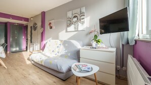 Une chambre à coucher moderne, avec un lit, une table de chevet, un téléviseur et des œuvres d’art.