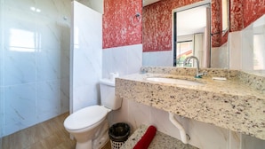 Ein Badezimmer mit einer weißen Toilette, einem Waschbecken mit einer Granitplatte und einem roten Handtuch auf dem Boden.