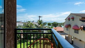 Ein Balkon mit Blick auf eine grüne Rasenfläche und ein Gebäude mit roten Dächern.