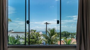 Ein Fenster mit Blick auf ein Wohngebiet, mit Häusern und Palmen.