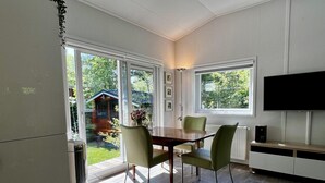 A modern kitchen with a dining area, large windows, and a flat-screen TV.