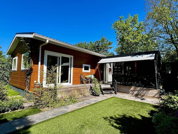 Une maison moderne avec une façade en bois, un porche abrité et une pelouse bien entretenue.