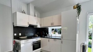 A modern kitchen with white cabinets, a black countertop, and a stainless steel trash can.