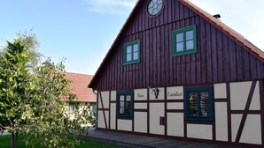 Ein traditionelles Fachwerkhäuschen mit zwei Fenstern, einem Schornstein und einer Uhr.