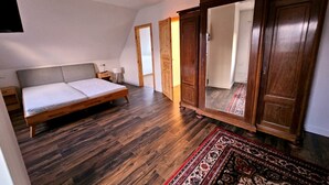 Ein Schlafzimmer mit Holzboden, einem Bett, einem Kleiderschrank und einem Spiegel.