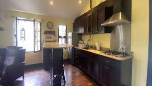 Una cucina compatta con mobili in legno scuro, una cappa aspirante in acciaio inossidabile e un forno a microonde integrato.
