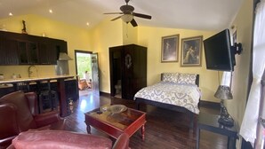 Una stanza con un letto, una scrivania, una sedia, una ventola a soffitto e una televisione.