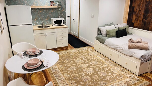 Une chambre compacte comprenant un lit, une table de chevet et une petite kitchenette.