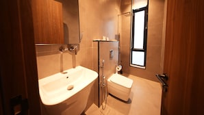 A modern bathroom with a bathtub, a toilet, and a shower area. - Nma a Residences 2 (Riyadh)