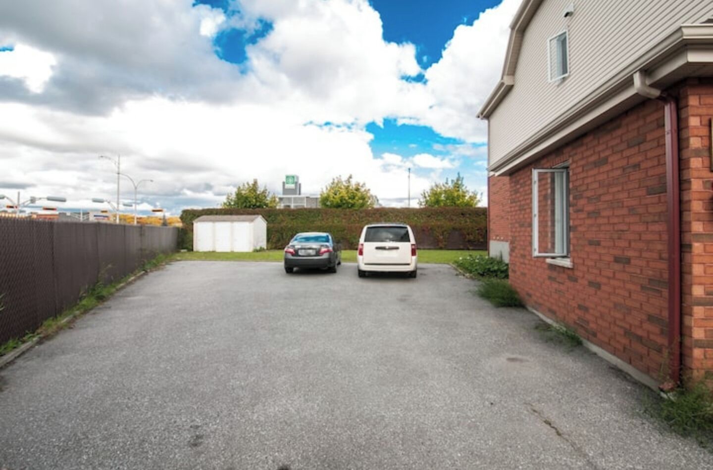 A parking area with two cars parked in front of a brick building.