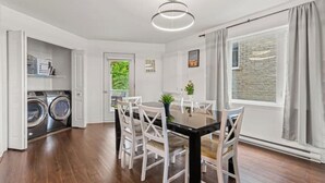 A modern kitchen with a dining area, built-in appliances, and a large window with curtains. - Lovely 2-bedroom Apt. in DIX30 close to DT (Brossard)