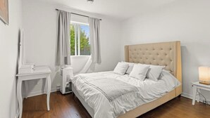 A bedroom with a bed, a bedside table, a lamp, a window with curtains, and a ceiling light. - Lovely 2-bedroom Apt. in DIX30 close to DT (Brossard)