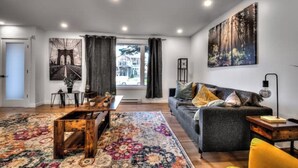 A modern living room with a sofa, coffee table, and a large window with curtains. - Lux. 4BR House with Pool near DT (Brossard)