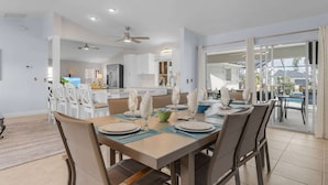Un coin repas avec une table dressée pour quatre personnes, une cuisine en arrière-plan et une vue sur l’extérieur.