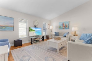 A living room with a television, a sofa, a coffee table, and a painting on the wall.