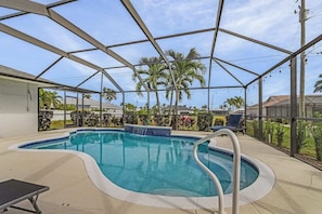 A covered swimming pool with a view of palm trees and houses.