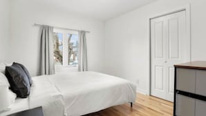 A bedroom with a bed, a wardrobe, a window with curtains, and a door. - Elegant 4 bedroom modern house (Brossard)