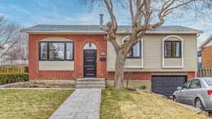 A two-story house with a brick facade, a front door, and a garage. - Elegant 4 bedroom modern house (Brossard)