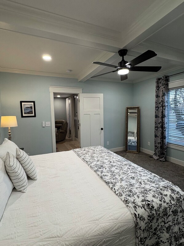 A bedroom with a bed, a ceiling fan, a door, a mirror, and a window with curtains. - Charming 4-bedroom, all new-century old treasure, located near Mercy hospital (Aurora)