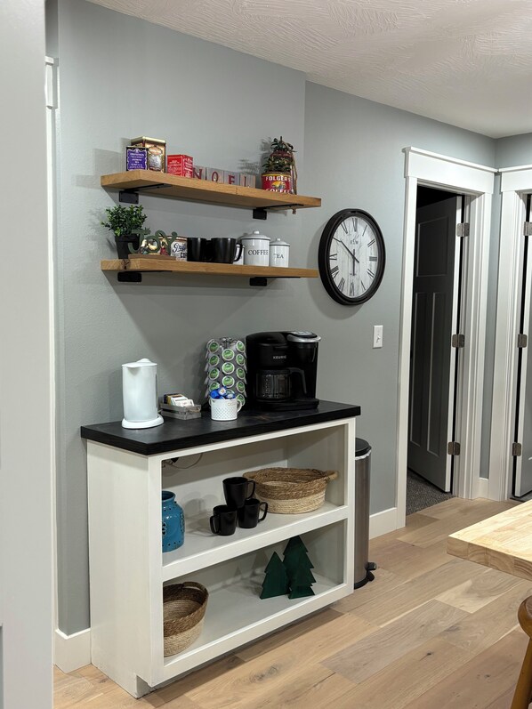 Eine Küche mit Holzböden, die Geschirr, eine Kaffeemaschine und eine Uhr an der Wand beherbergt.