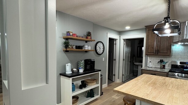 A modern kitchen with a wooden island, built-in shelves, and a hanging light fixture. - Charming 4-bedroom, all new-century old treasure, located near Mercy hospital (Aurora)