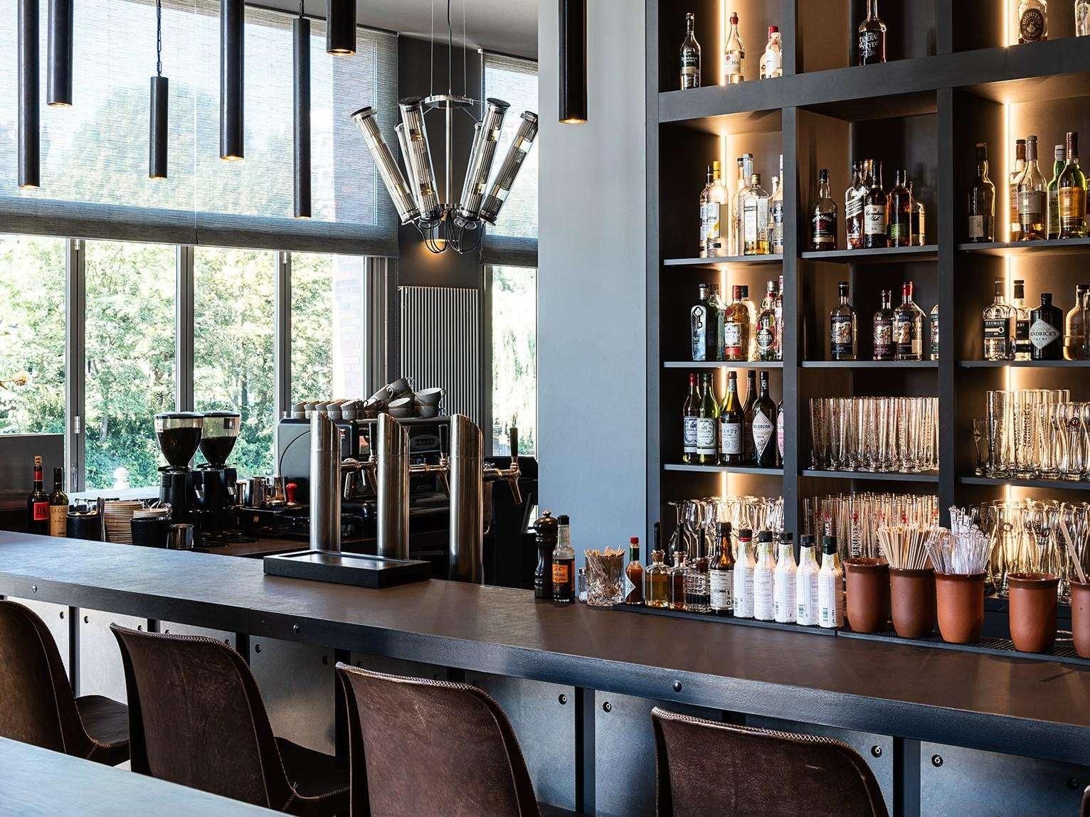 A bar area with a coffee machine, shelves of liquor bottles, and a variety of glasses.
