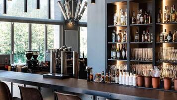 A bar area with a coffee machine, shelves of liquor bottles, and a variety of glasses.