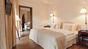A hotel room with a large bed, two bedside lamps, a wooden nightstand, and a TV mounted on the wall. - Abion Villa Suites (Berlin)