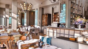A modern restaurant with high ceilings, exposed brick walls, and a central bar area. - Abion Villa Suites (Berlin)