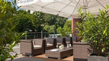 An outdoor seating area with wicker furniture and umbrellas.