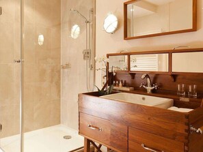 A bathroom with a wooden vanity, a large mirror, and a glass shower enclosure. - Abion Villa Suites (Berlin)