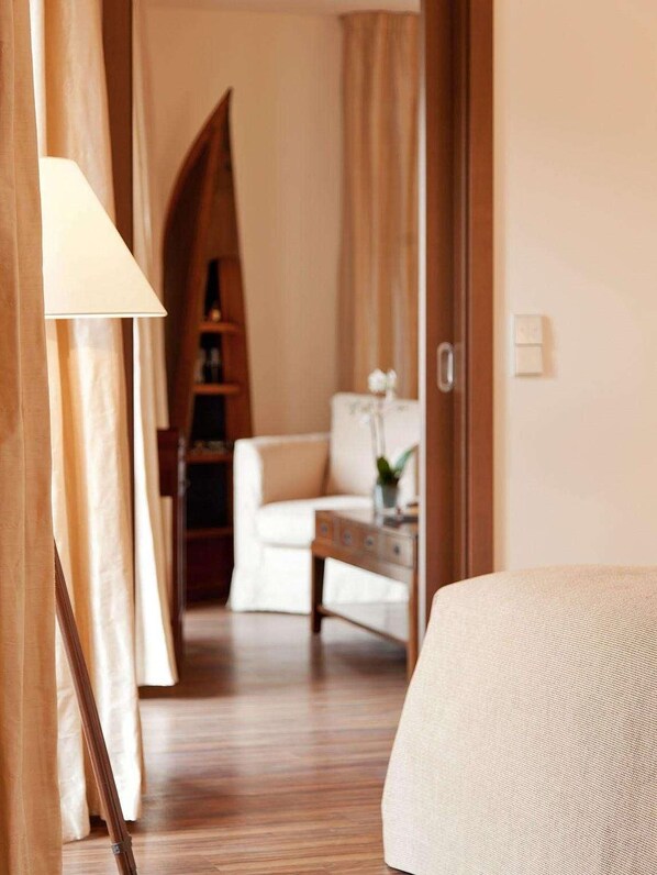 A hotel room with a bed, a desk, and a chair. There is a lamp on the desk and a plant on the floor. - Abion Villa Suites (Berlin)
