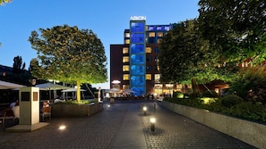 A hotel entrance with a clear pathway leading to the building, outdoor seating area, and well-lit surroundings. - Abion Villa Suites (Berlin)