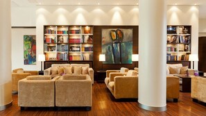 A spacious lobby with multiple seating areas, a large bookshelf filled with books, and a prominent abstract painting. - Abion Villa Suites (Berlin)