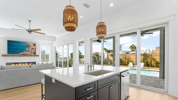 A modern kitchen with a large island, a built-in oven, and a view of a swimming pool. - Tango Vista With Pool, Elevator, And Beach Views (Miramar Beach)